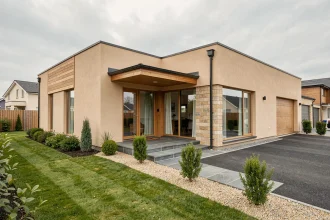 Pavillon clé en main moderne en enduit beige avec bardage bois, jardin aménagé et allée en gravier, vue extérieure grand angle